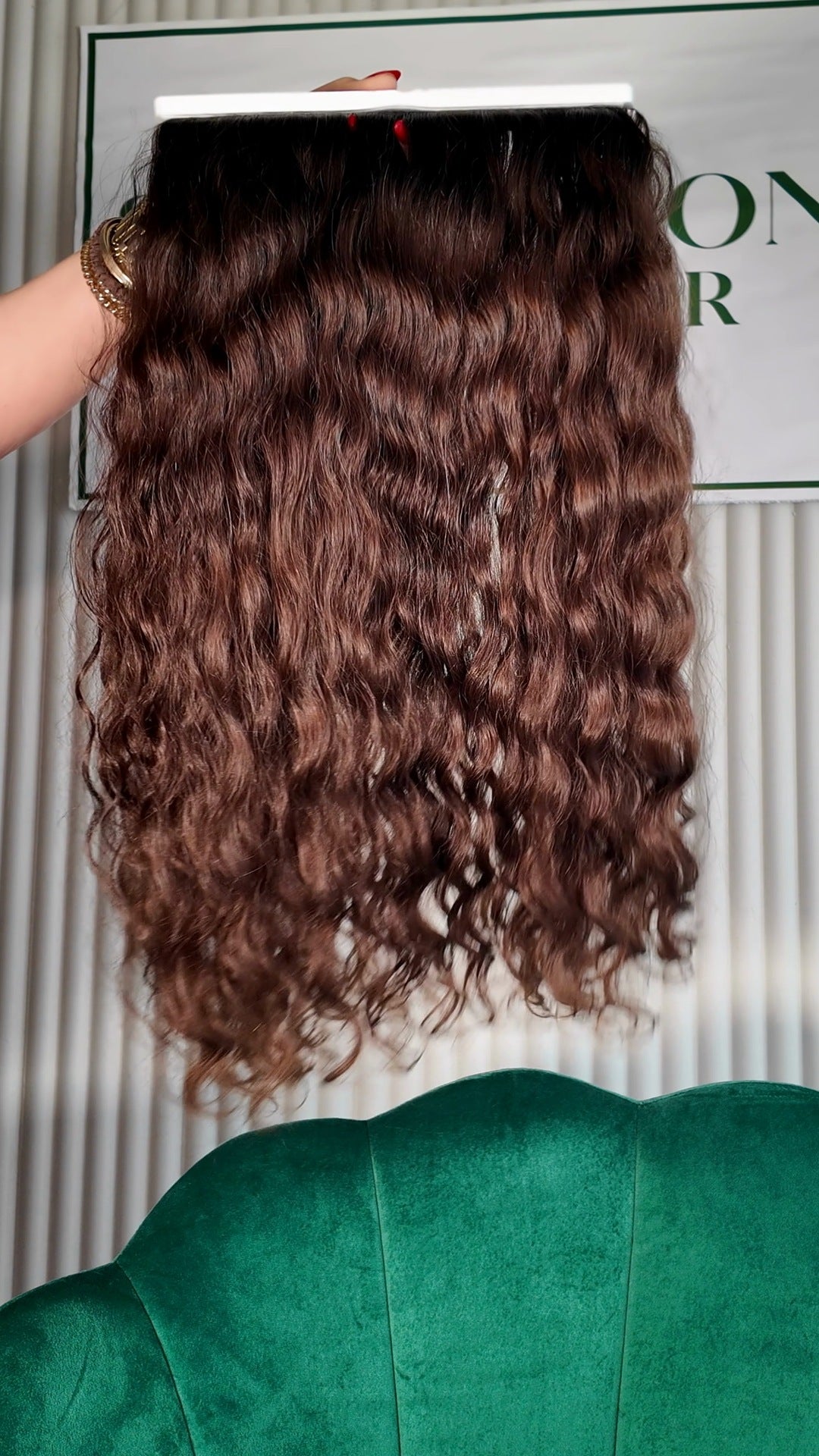 24 inch Russian single donor virgin hair tail in chestnut brown, held up against the Stevi Pisoni Virgin Hair backdrop