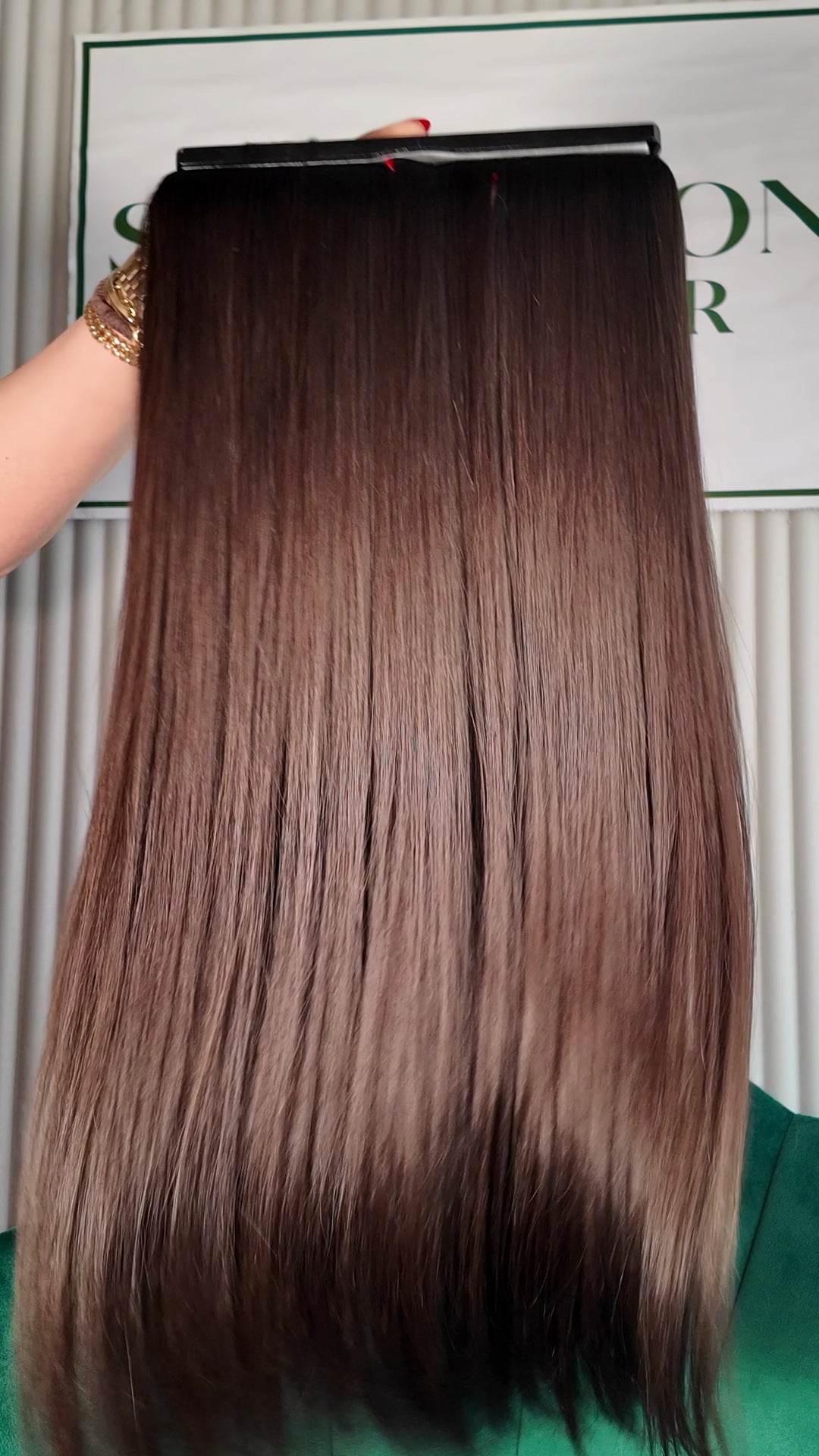 31 inch Russian single donor virgin hair tail in natural black / dark brown, held up against the Stevi Pisoni Virgin Hair backdrop