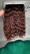 24 inch Russian single donor virgin hair tail in chestnut brown, held up against the Stevi Pisoni Virgin Hair backdrop