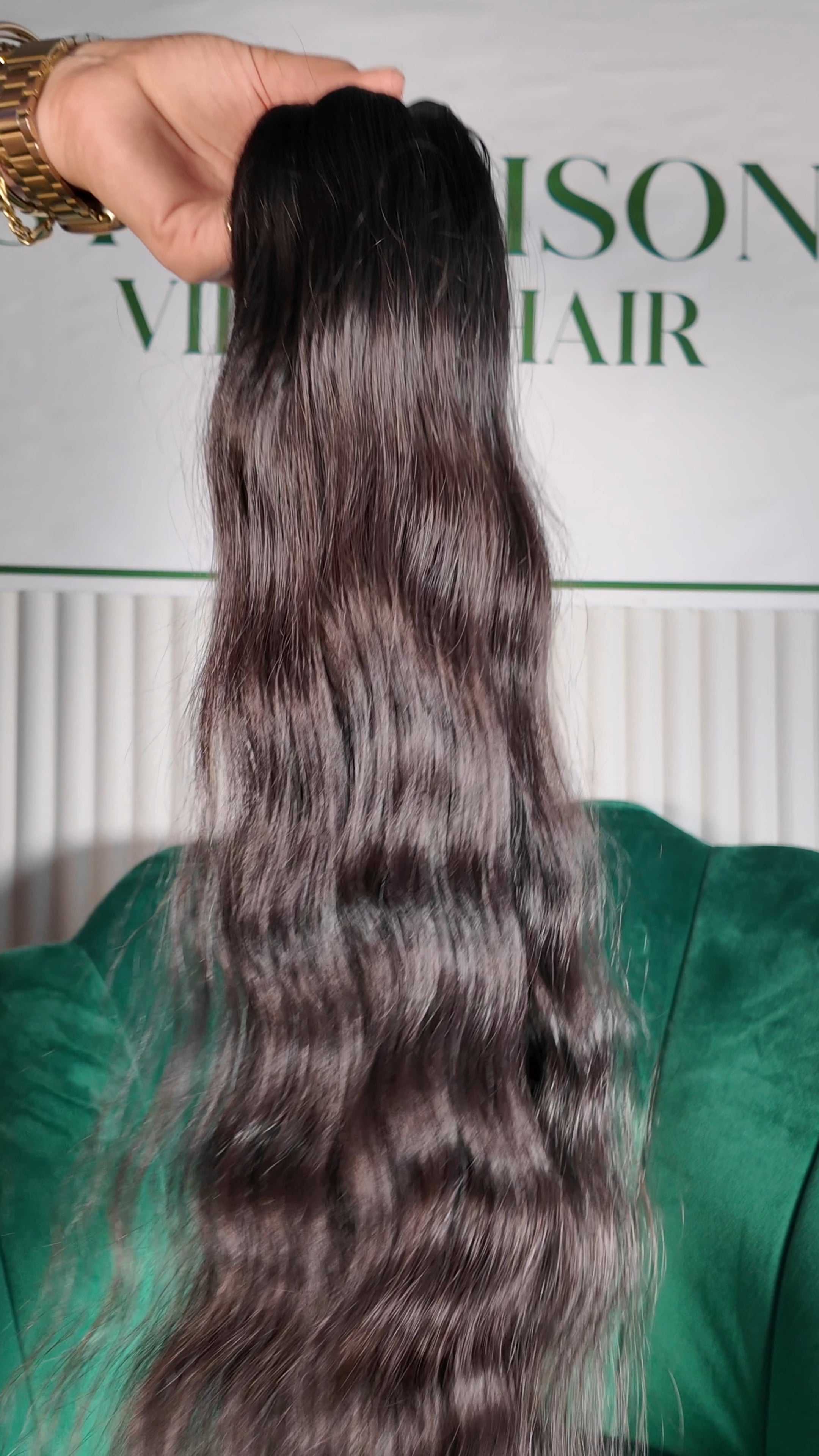 30 inch Russian single donor black virgin silky wavy hair tail, held up against the Stevi Pisoni Virgin Hair backdrop