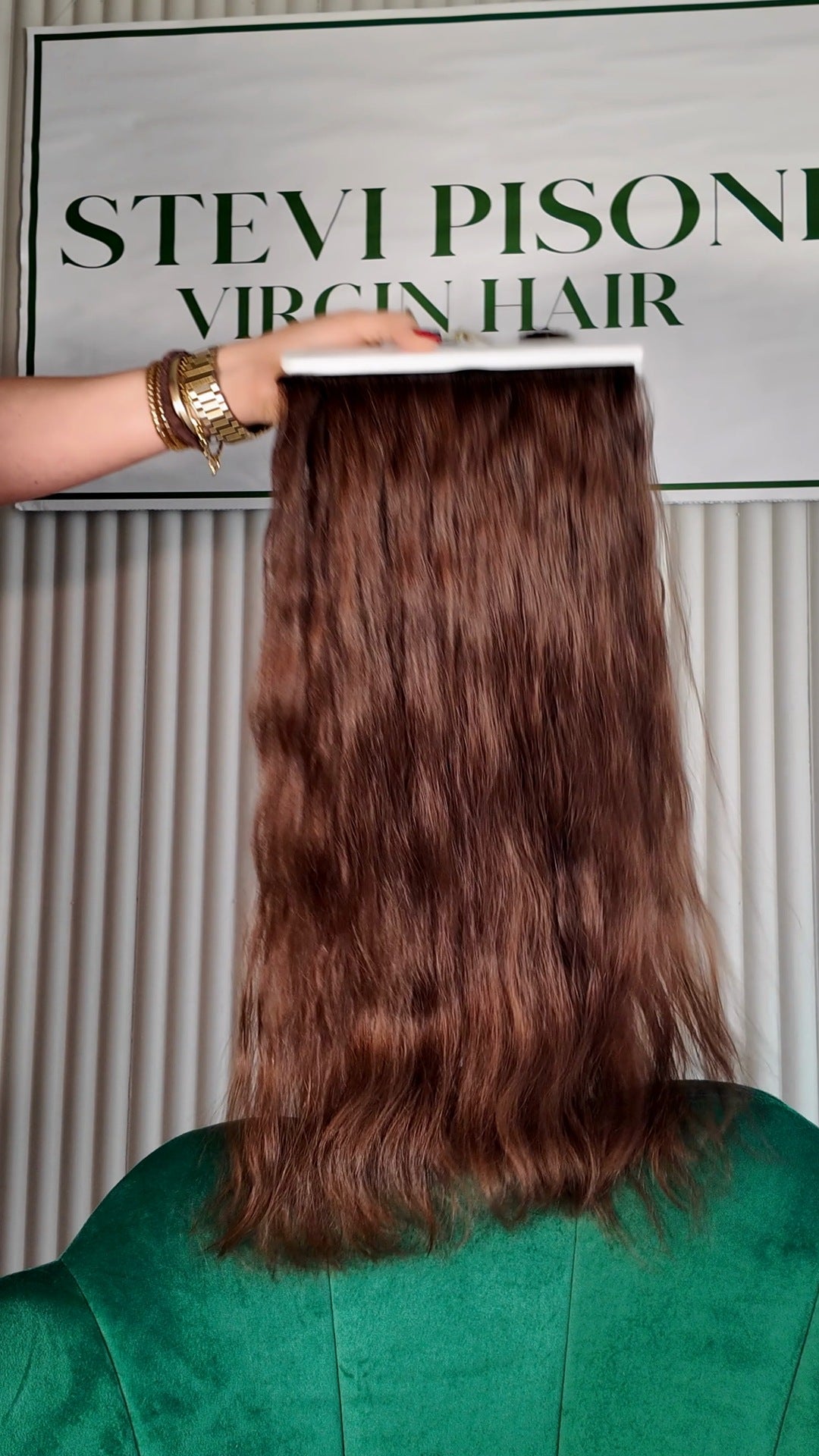 32 inch Russian single donor virgin hair tail in chestnut brown, held up against the Stevi Pisoni Virgin Hair backdrop