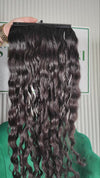 28.5 inch Russian single donor virgin curly dark brown hair tail held against the Stevi Pisoni Virgin Hair backdrop
