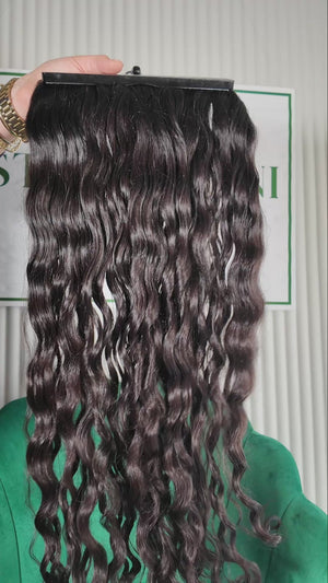 28.5 inch Russian single donor virgin curly dark brown hair tail held against the Stevi Pisoni Virgin Hair backdrop