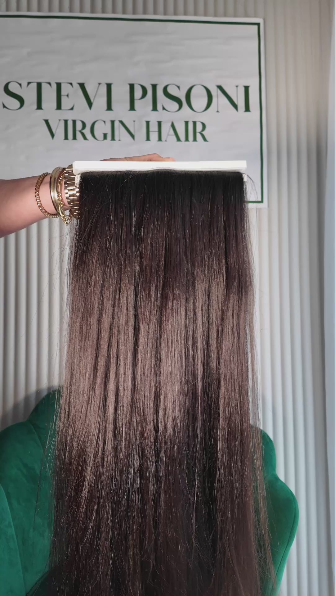 32 inch Russian single donor virgin hair tail in natural black / dark brown held against the Stevi Pisoni Virgin Hair backdrop