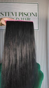 32 inch Russian single donor dyed black virgin hair tail held against the Stevi Pisoni Virgin Hair backdrop