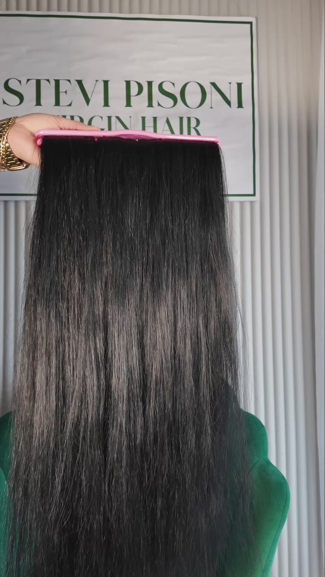 32 inch Russian single donor dyed black virgin hair tail held against the Stevi Pisoni Virgin Hair backdrop